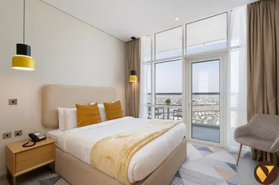 a bedroom with a large bed and a large window at Vogue JVT Novotel near Springs Souk Mall, One Bedroom apartment with Balcony and Vibrant Community View, Access to all Amenities in Dubai