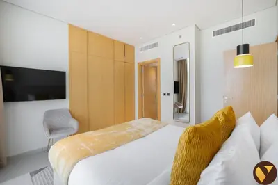 a hotel room with a bed and a tv at Vogue JVT Novotel near Springs Souk Mall, One Bedroom apartment with Balcony and Vibrant Community View, Access to all Amenities in Dubai