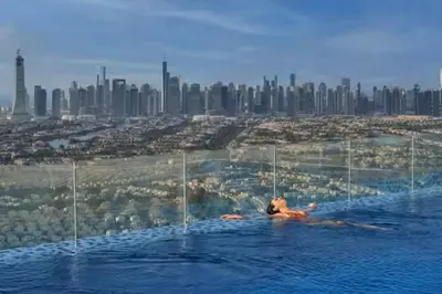 a person in a swimming pool with a city in the background at Vogue JVT Novotel near Springs Souk Mall, One Bedroom apartment with Balcony and Vibrant Community View, Access to all Amenities in Dubai