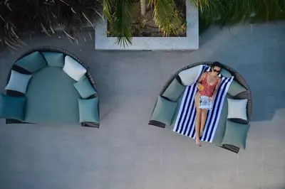 a woman is sitting on a beach chair at Vogue JVT Novotel near Springs Souk Mall, One Bedroom apartment with Balcony and Vibrant Community View, Access to all Amenities in Dubai