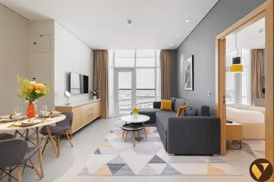 a living room with a couch and a table at Vogue JVT Novotel near Springs Souk Mall, One Bedroom apartment with Balcony and Vibrant Community View, Access to all Amenities in Dubai