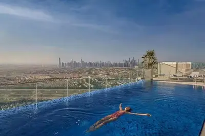 a man swimming in a swimming pool with a view at Vogue JVT Novotel near Springs Souk Mall, Studio Apartment with Balcony and City View, Access to all Amenities in Dubai