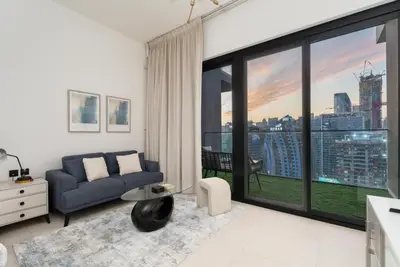 a living room with a couch and a large window at GuestReady - Studio l Partial Burj Khalifa View in Dubai