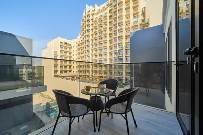 a table and chairs on a balcony with a building at Fresh and Modern 1BR Welcome to Asak 11 JVC in Dubai