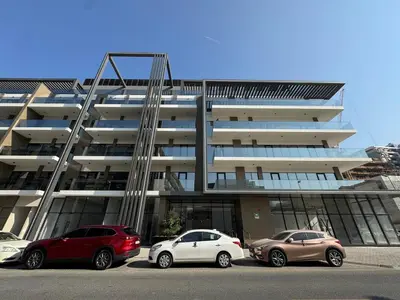 three cars parked in a parking lot in front of a building at Fresh and Modern 1BR Welcome to Asak 11 JVC in Dubai
