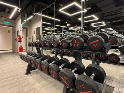 a row of dumbbell racks in a gym at Fresh and Modern 1BR Welcome to Asak 11 JVC in Dubai