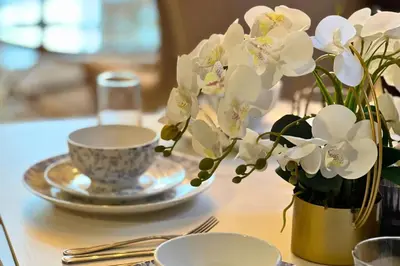 a table with a vase of white flowers and a cup at Coozy one bedroom in Al Jaddaf Dubai in Dubai