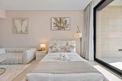 a white bedroom with a large bed and a couch at Private Jacuzzi Canal view - Near Burj Khalifa in Dubai