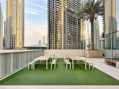 a patio with tables and chairs on a balcony with tall buildings at PVH - Contemporary 1BR Near Burj Khalifa - Forte Tower 2 in Dubai