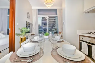 a dining room with a table with plates and glasses at 1BR Facing Canal and City Views, Just a Short Walk to Bus Stop and Marine Transport, Reva Residences, Business Bay by Deluxe Holiday Homes in Dubai