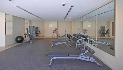 a gym with several tread machines and a mirror at 1BR Facing Canal and City Views, Just a Short Walk to Bus Stop and Marine Transport, Reva Residences, Business Bay by Deluxe Holiday Homes in Dubai