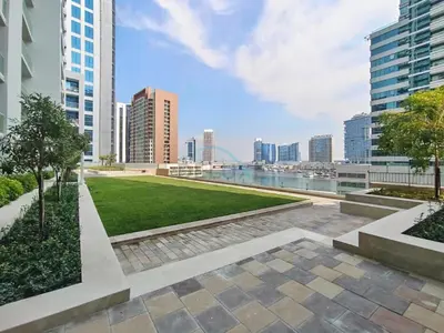 a park in the middle of a city with tall buildings at 1BR Facing Canal and City Views, Just a Short Walk to Bus Stop and Marine Transport, Reva Residences, Business Bay by Deluxe Holiday Homes in Dubai