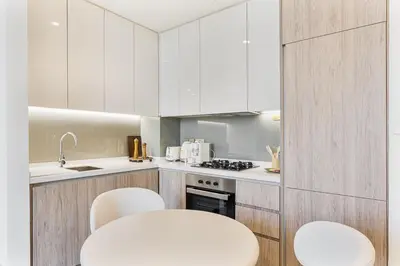 a kitchen with white cabinets and white stools at Luxury 1Bed with Canal Views Near Burj Khalifa in Dubai
