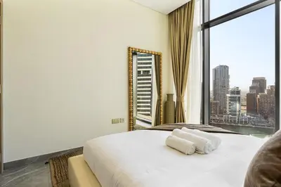 a bedroom with a large white bed with a large window at Luxury 1Bed with Canal Views Near Burj Khalifa in Dubai