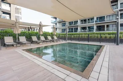 a swimming pool with chairs and a building at StayShort - 1 Bedroom Sleeps 2 with City Views in Business Bay in Dubai