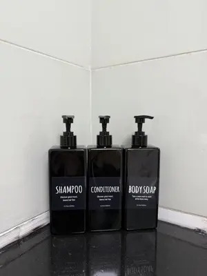 three bottles of soap sitting on a counter at Spacious 1Bed with Golf Course and Marina View in Dubai