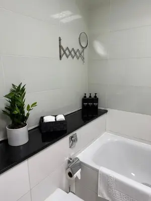 a white bathroom with a white tub and a plant at Spacious 1Bed with Golf Course and Marina View in Dubai