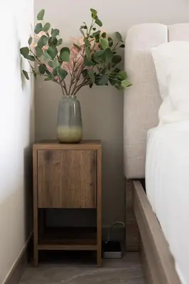 a vase on a night stand next to a bed at Cozy studio with Burj Khalifa and canal view in Dubai