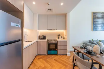 a kitchen and dining room with a table and a refrigerator at ShoresInn - Luxury Dubai Creek Harbour Stay in Dubai