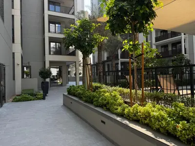 a courtyard of a building with trees and plants at Elegant 1BR at Lotus Creek Beach Lagoon Living in Dubai