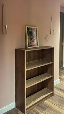 a wooden book shelf in a room with a painting at Modern Japanese and Arabic Fusion City Stay that is 10 min from Dubai Mall in Dubai