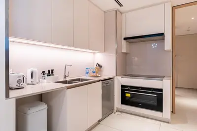 a small kitchen with white cabinets and a sink at HAVN - 3 Bedroom in The Address, JBR in Dubai