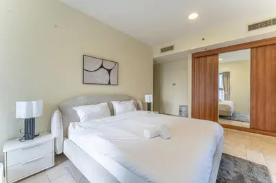 a bedroom with a large white bed and a mirror at HAVN - High Floor 2 Bedroom in Marina, near Tram in Dubai