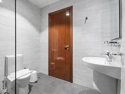 a bathroom with a toilet and a sink and a wooden door at Urban Elegance 1BDR in Dunya 06 in Dubai