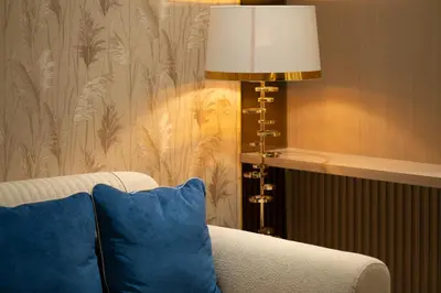a lamp sitting next to a couch with a blue pillow at The Royal Blue Jacuzzi Suite 32 1-6-10 I JVC I Dar Oasis in Dubai