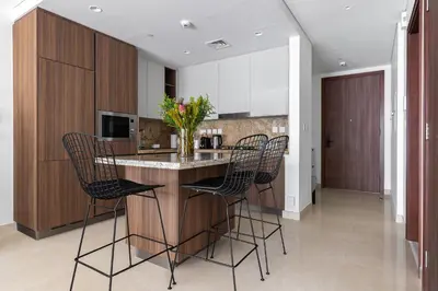 a kitchen with a island with chairs around it at Downtown Dubai - Bright 1BR Apartment - Imperial Avenue in Dubai