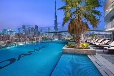 a swimming pool with a palm tree on top of a building at Vacationer I Premium 2 Bedroom Apartment I Iconic Burj Khalifa View I Downtown I Distinction Tower in Dubai