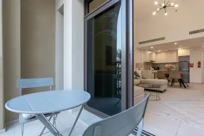 a dining room with a table and chairs and a living room at Jumeirah Stay Near To Beach in Dubai