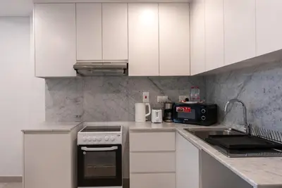 a kitchen with white cabinets and a stove top oven at Jumeirah Stay Near To Beach in Dubai
