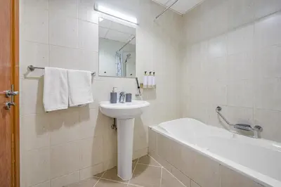 a white bathroom with a sink and a bath tub at Spacious 1BR Magnolia 1 JVC in Dubai