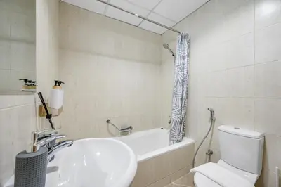 a bathroom with a sink and a toilet and a tub at Spacious 1BR Magnolia 1 JVC in Dubai