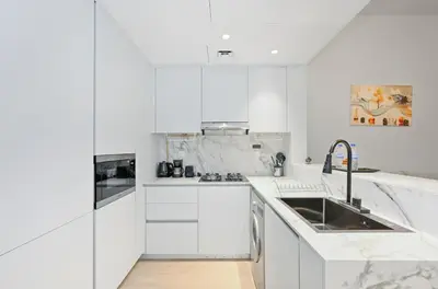 a white kitchen with white cabinets and a sink at Bloomfields Comfort Studio at Bali Residence, DXB in Dubai