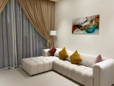a living room with a white couch with colorful pillows at The Executive Suite Luxury 1 Bedroom Brand New in Dubai