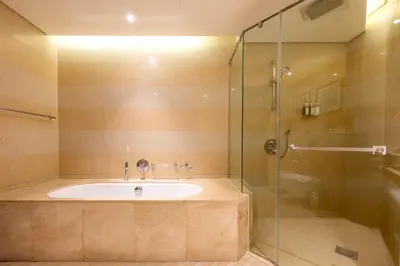 a bathroom with a tub and a glass shower at City View 1 BR - Creek Heights, Upgraded by UDH in Dubai