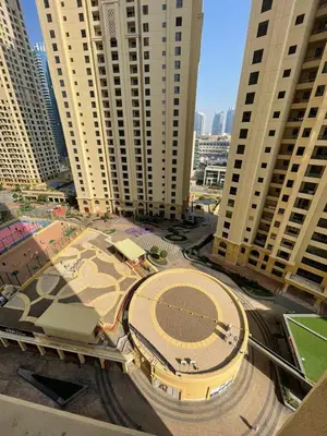 a large building with a tennis court in front of tall buildings at Two Bedroom Apartment with Excellent Location in Dubai