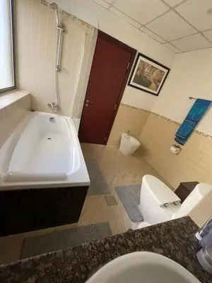 a bathroom with a tub and a toilet and a sink at Two Bedroom Apartment with Excellent Location in Dubai