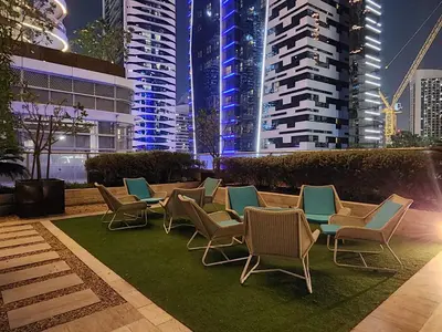 a group of chairs sitting on a lawn with buildings at Damac Maison Mall Street LARGE 2BR I Full Burj Views I Connects Dubai Mall in Dubai