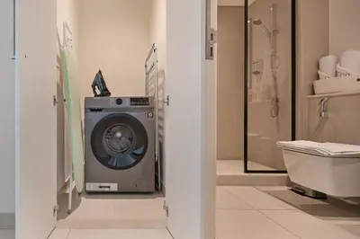 a bathroom with a washing machine and a toilet at Stylish 1BR, Walk to Burj Khalifa and Dubai Mall in Dubai