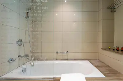 a bathroom with a bath tub with a glass shower at GuestReady - Chic Damac Paramount | Business Bay in Dubai