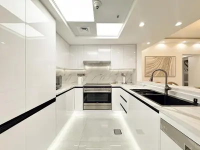 a white kitchen with white cabinets and a sink at Dream Shoma-2BR - Pool - Walk to Burj Khalifa in Dubai