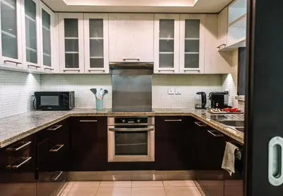 a kitchen with white cabinets and a stove top oven at Burj Khalifa 1BR Pool Gym Sauna Dubai Mall in Dubai