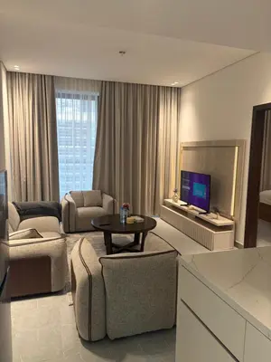 a living room with a tv and a couch and a table at Modern Downtown 1BR Apartment in jumeirah Garden in Dubai
