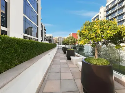 a balcony with a row of potted trees on a building at Chic Studio in Azizi Riviera Minutes to Downtown in Dubai