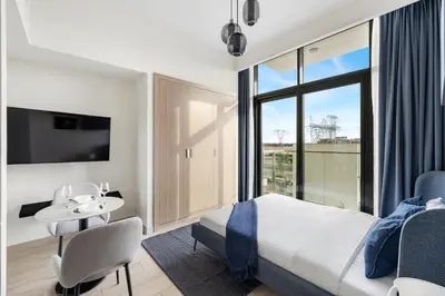 a bedroom with a bed and a table and a tv at Chic Studio in Azizi Riviera Minutes to Downtown in Dubai