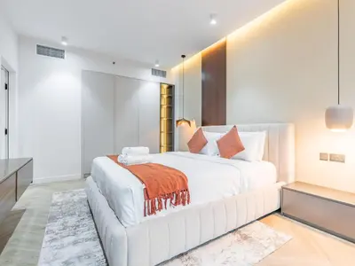 a white bedroom with a large white bed with an orange blanket at Waterfront 1BR- Time Place Dubai Marina-City Views in Dubai