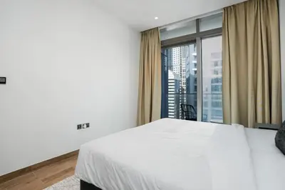 a bedroom with a white bed and a large window at CitiHome Refined 1BR Jumeirah Living Marina Gate in Dubai